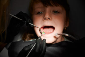How to Help Kids With Dental Anxiety: Tips for Parents in Crystal Lake 2 Dentist examining young girl’s teeth during pediatric dental checkup