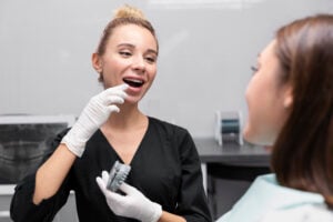 Are Dental Implants Safe? What Patients Need to Know in 2026 1 Dental professional showing a dental implant model while discussing implant treatment with a patient.