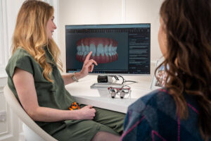 What Does a Dental Implant Look Like Before the Crown Is Placed? 2 Dentist reviewing a digital dental implant crown design with a patient during a restorative treatment consultation.