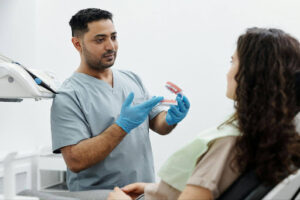 Dental Implants vs Dentures: Which Is Right for You? 2 Dentist explaining denture treatment options to a patient using a dental model