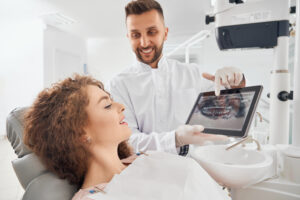 Individual Tooth Implants: A Permanent Solution for a Missing Tooth 1 Dentist reviewing a digital scan of a patient's jaw before implant treatment.