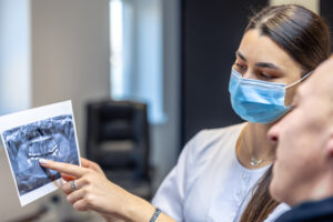 What Can a Dentist Do for Receding Gums? Treatment Options Explained 2 Dentist pointing to a dental x-ray while discussing gum health with a patient.