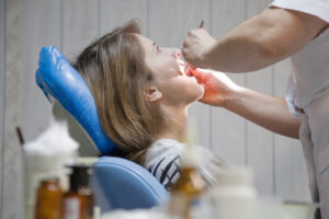 Broken Crown or Loose Dental Bridge: What to Do in a Dental Emergency 2 Dentist examining a female patient’s teeth during a routine dental checkup.