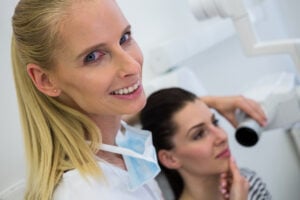 Cosmetic Dentistry in Crystal Lake: Veneers, Whitening & Bonding Explained 1 Dentist taking a dental X-ray of a female patient during an exam.