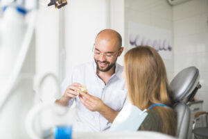 Dental Crowns Near Me: Why Crystal Lake Patients Trust Our Team 2 Dentist explaining a dental model to a female patient during a consultation.